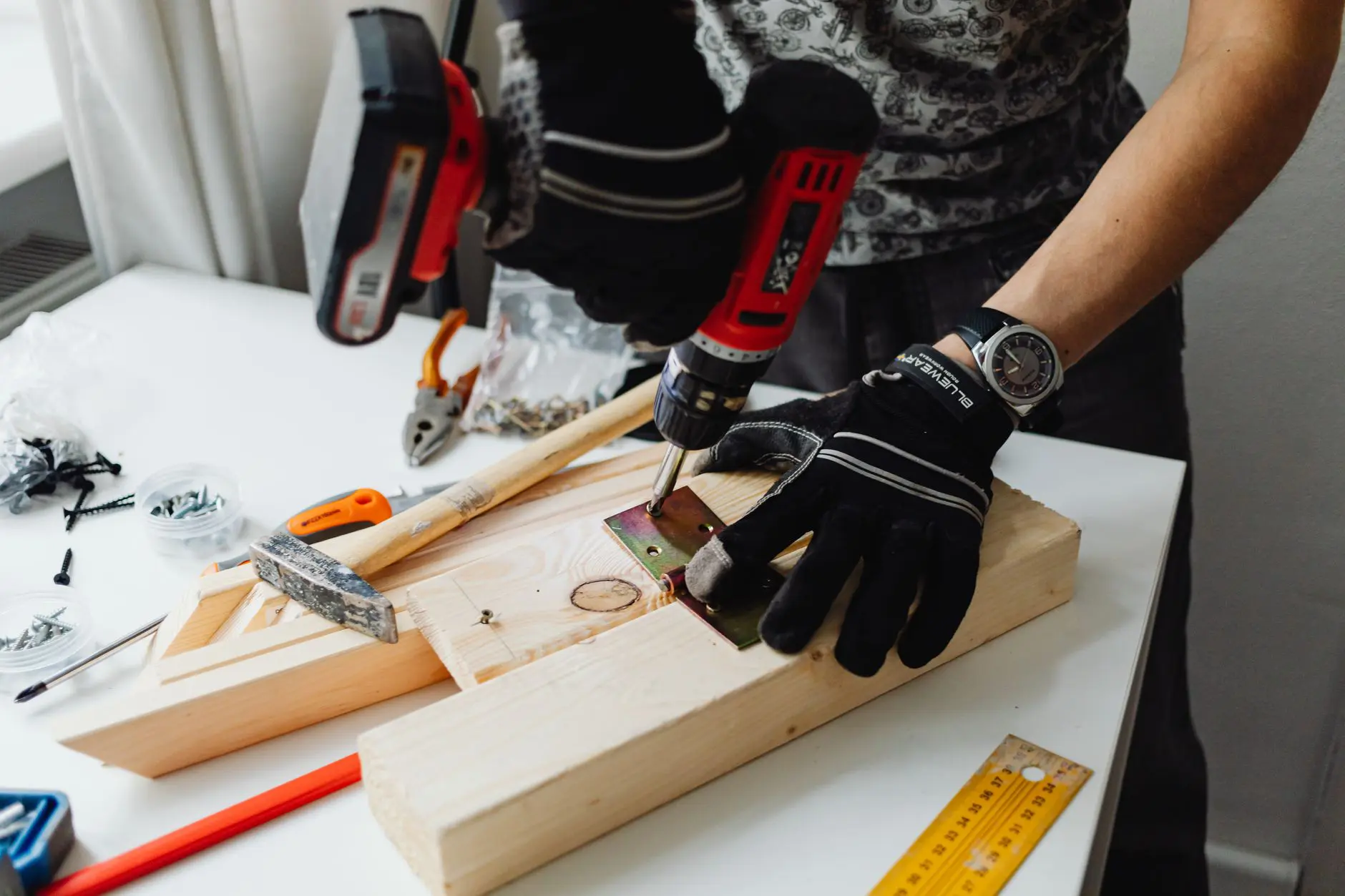 Un artisan utilise une perceuse électrique sur du bois, démontrant ainsi son savoir-faire et ses compétences en menuiserie.